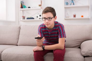 Televizyon izlerken, uzaktan kumanda ile genç çocuk