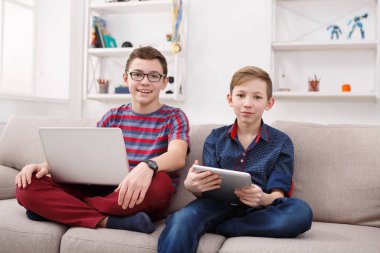 İki genç çocuklar evde kanepede gadget'lar ile