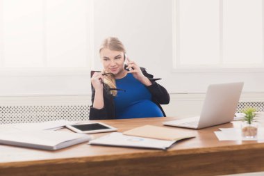 Hamile iş kadını telefonda konuşurken iş başında