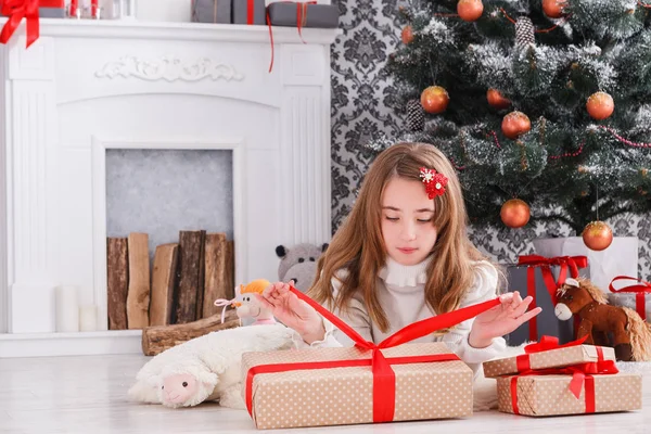 Hermosa chica en santa hat desenvolver regalos de Navidad —  Fotos de Stock