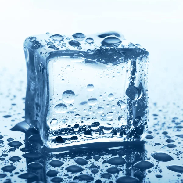Transparenter Eiswürfel auf blauem Glas mit Wassertropfen — Stockfoto