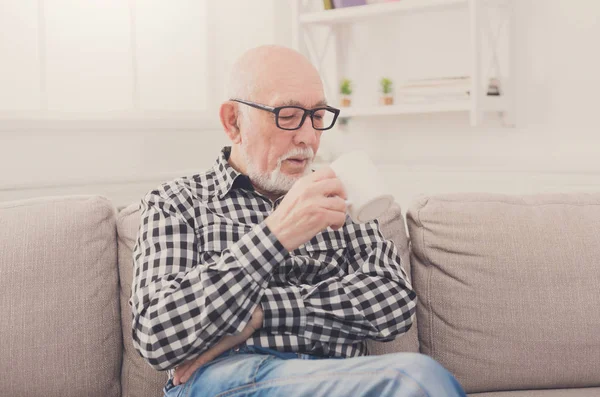 Senior man having cup of coffee in living room — Stock Photo, Image