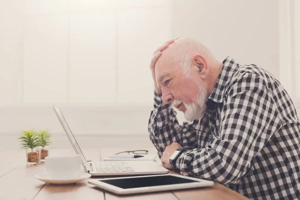 Besorgter Senior nutzt Laptop zu Hause — Stockfoto