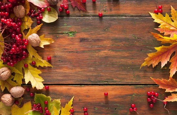 Sonbahar akçaağaç sarı yaprakları ve ahşap arka plan üzerinde çilek