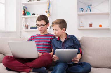 İki genç çocuklar evde kanepede gadget'lar ile