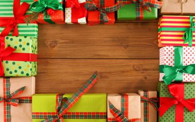 Noel hediye kutuları ahşap arka plan üzerinde bir sürü görünümü top. Zanaat ve renkli kağıt hediye kırmızı ve yeşil şerit yay ile dekore edilmiştir. Kopya alanı