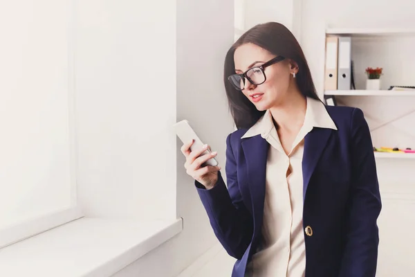 Mulher de negócios com telefone celular na janela do escritório — Fotografia de Stock