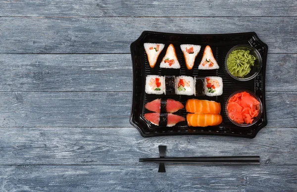 Ιαπωνικά τρόφιμα παράδοσης. Σύνολο σούσι και ρόλους θέα πάνω στο ξύλο — Φωτογραφία Αρχείου
