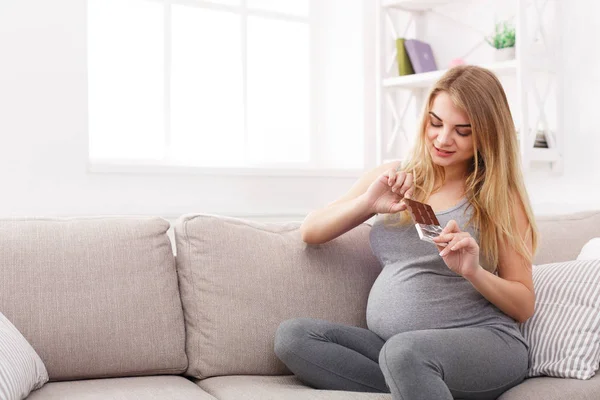 Młoda kobieta w ciąży, jedzenie czekolady — Zdjęcie stockowe