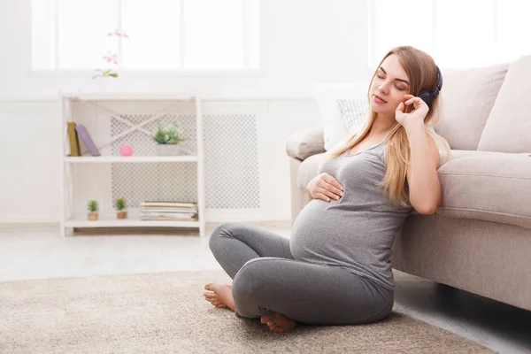 Wanita hamil mendengarkan musik di headphone — Stok Foto