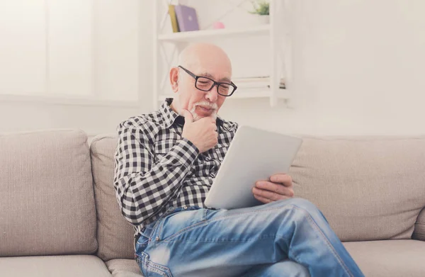 Senior man reading news on digital tablet — Stock Photo, Image