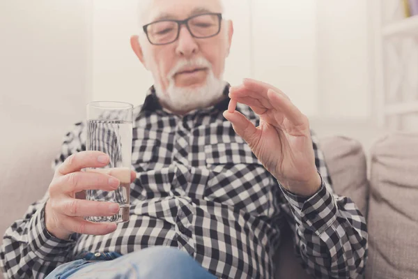 Old man having a glass of water and pills in hand — Stock Photo, Image