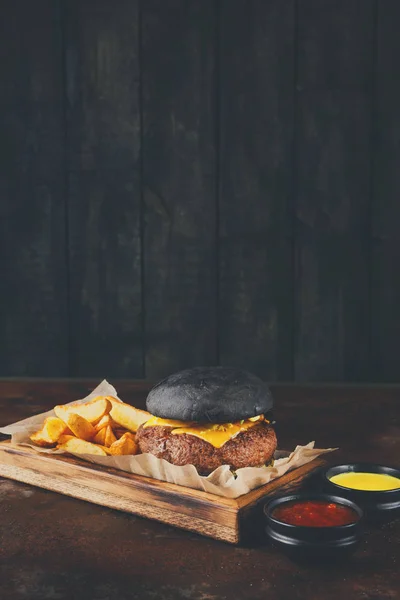 Black bun burger with potato wedges copy space — Stock Photo, Image