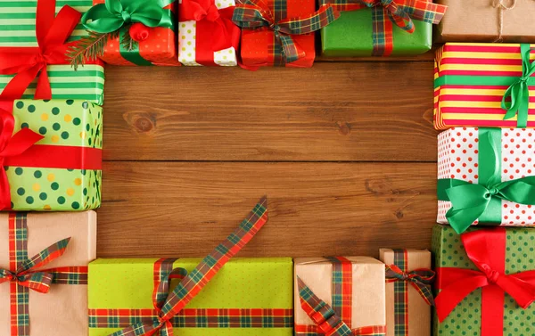 Noel hediye kutuları ahşap arka plan üzerinde bir sürü görünümü top. Zanaat ve renkli kağıt hediye kırmızı ve yeşil şerit yay ile dekore edilmiştir. Kopya alanı