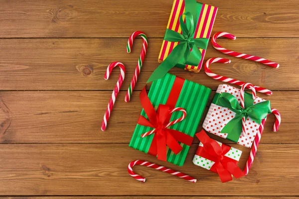 Karácsonyi ajándék dobozok, candy, rusztikus háttér. Bemutatja a piros, zöld szalag íjak díszített. Szemközti nézet — Stock Fotó