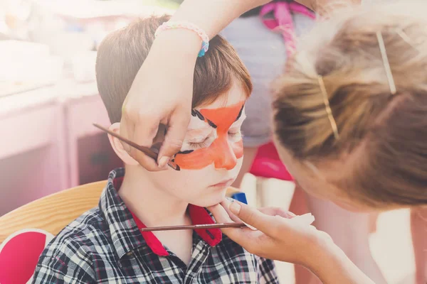 Child boy face painting, making tiger eyes process