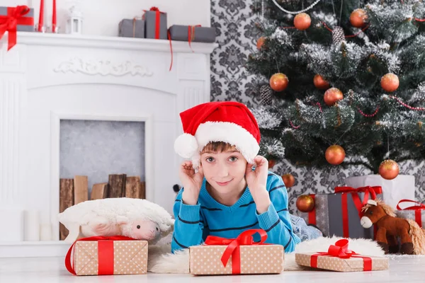 Mignon garçon dans santa chapeau déballer cadeaux de Noël — Photo