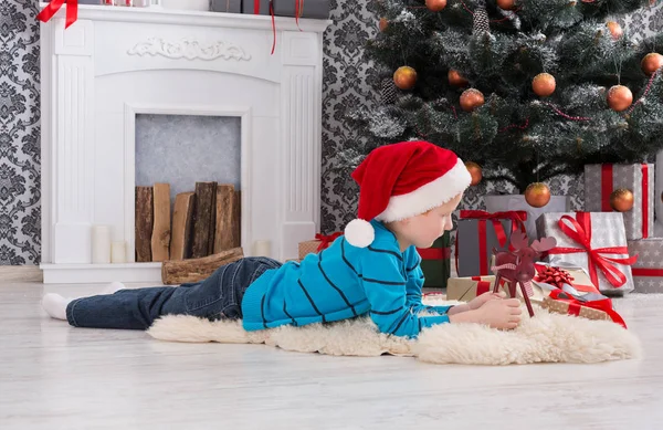 Милий щасливий хлопчик в капелюсі Санта з іграшковими різдвяними подарунками — стокове фото