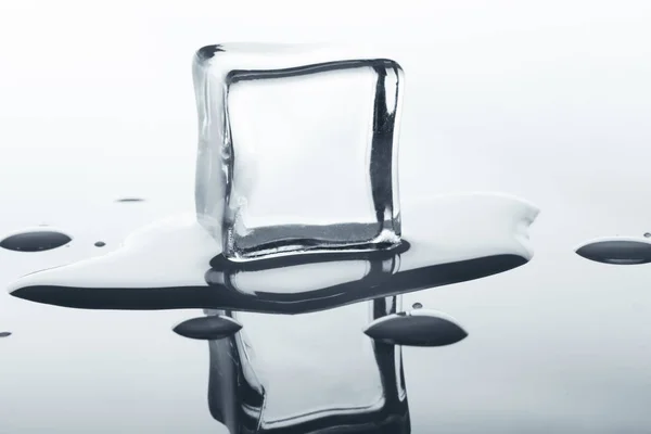 Schmelzender Eiswürfel mit Reflexion auf Weiß. — Stockfoto