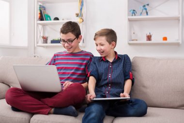 İki genç çocuklar evde kanepede gadget'lar ile