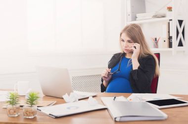 Hamile iş kadını telefonda konuşurken iş başında