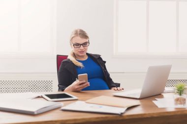 Ofiste Smartphone kullanan genç hamile kadın