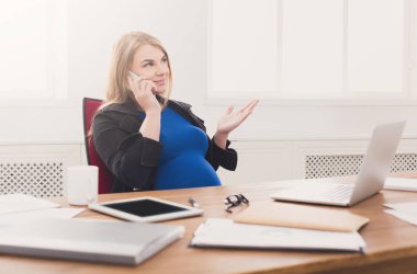 Hamile iş kadını telefonda konuşurken iş başında