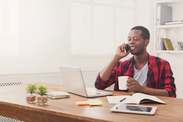 Joven hombre de negocios negro hablando en el móvil en la oficina blanca moderna —  Fotos de Stock