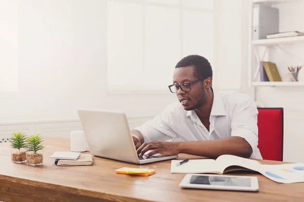 Μαύρο επιχειρηματίας στο λευκό γραφείο, εργασία με φορητό υπολογιστή — Φωτογραφία Αρχείου