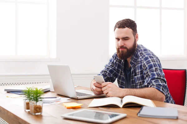 Ung det manager i office med mobiltelefon av den bärbara datorn — Stockfoto