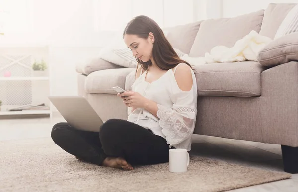 Ragazza con un computer portatile messaggistica sul cellulare — Foto Stock