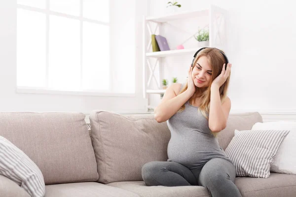 Těhotná žena poslechu hudby ve sluchátkách — Stock fotografie