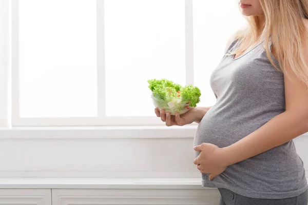 Mujer embarazada joven comiendo ensalada verde fresca, espacio para copiar . — Foto de Stock