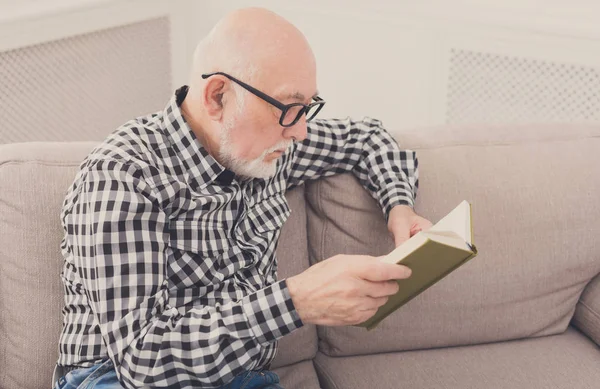 Senior Mann liest Buch zu Hause, Kopierraum — Stockfoto