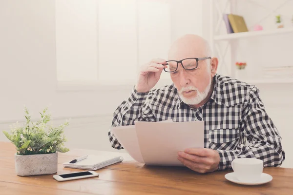 Geschockter Senior schaut auf Scheine — Stockfoto