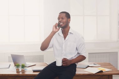 Modern beyaz ofis cep konuşurken genç siyah işadamı
