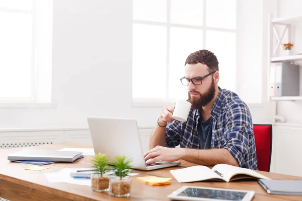Joven manager masculino en gafas trabajando con laptop en moderna oficina blanca — Foto de Stock
