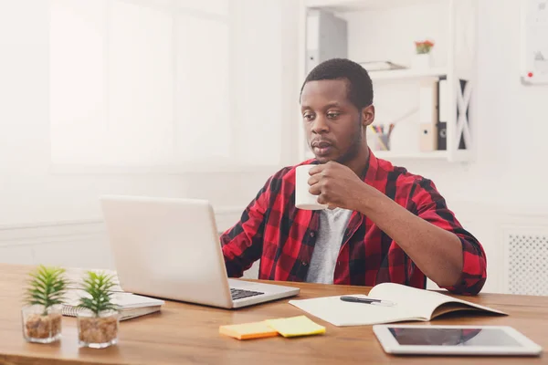 Ontspannen zwarte zakenman in casual kantoor, werk met laptop, koffie drinken — Stockfoto