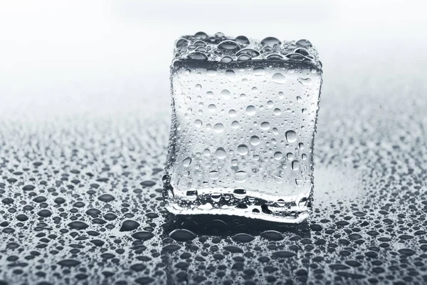Cubo de gelo transparente em vidro com gotas de água — Fotografia de Stock