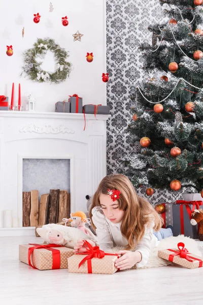 Hermosa chica en santa hat desenvolver regalos de Navidad —  Fotos de Stock