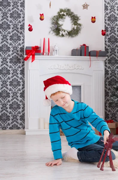 Bonito menino feliz em santa chapéu com presentes de Natal de brinquedo — Fotografia de Stock