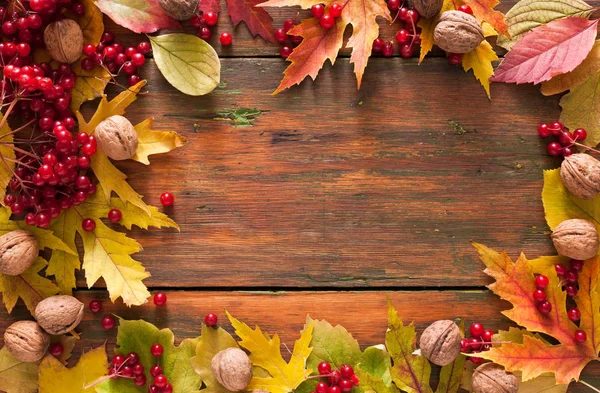 Sonbahar akçaağaç sarı yaprakları ve ahşap arka plan üzerinde çilek