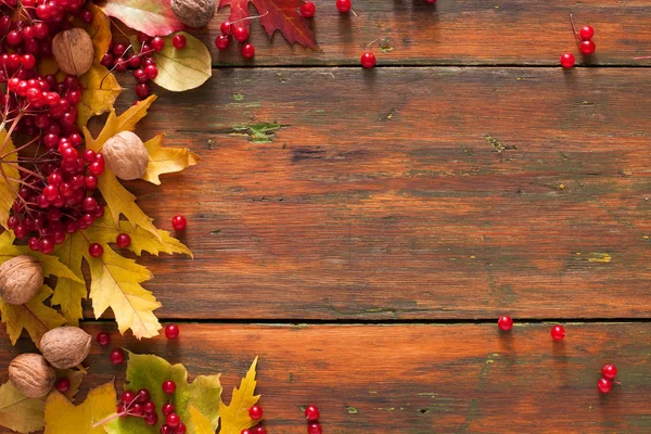 Sonbahar akçaağaç sarı yaprakları ve ahşap arka plan üzerinde çilek