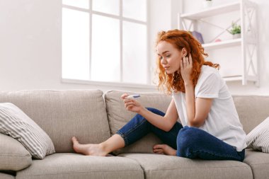 Endişeli kız onun gebelik testinin sonuçlarını okuma