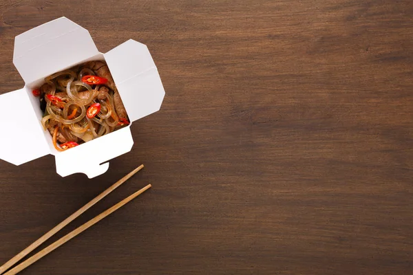 Asiatisches Essen im Lieferkarton auf Holztisch — Stockfoto