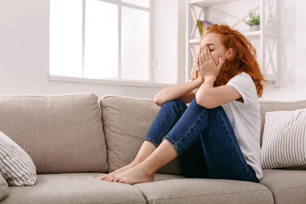 Mujer pelirroja triste pensando en sofá beige —  Fotos de Stock