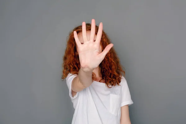 Młoda kobieta zasłaniając twarz z palm — Zdjęcie stockowe