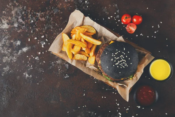 Hamburguesa de bollo negro con cuñas de papa vista superior —  Fotos de Stock