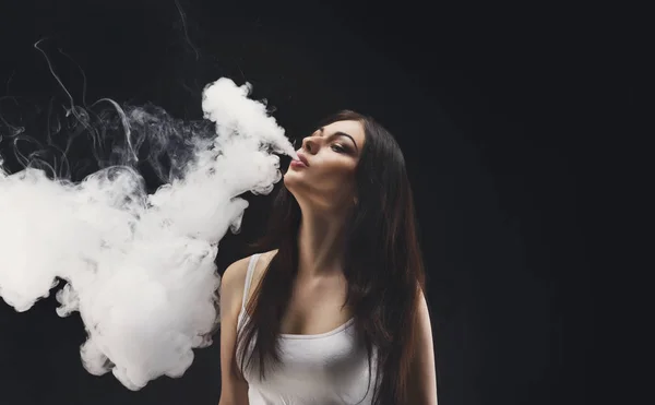 Mujer joven vapeando e-cigarrillo con humo en negro — Foto de Stock