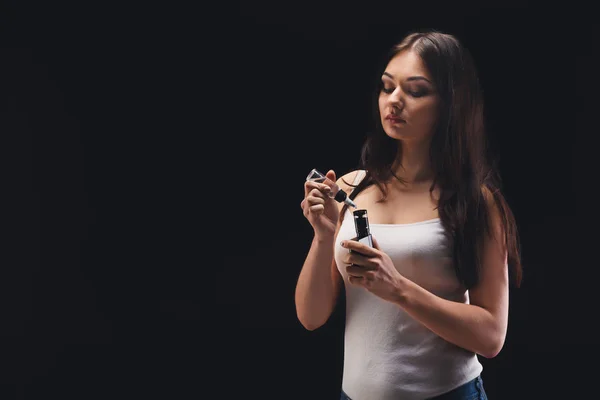 Junge Frau füllt Flüssigkeit in E-Zigarette auf schwarz — Stockfoto